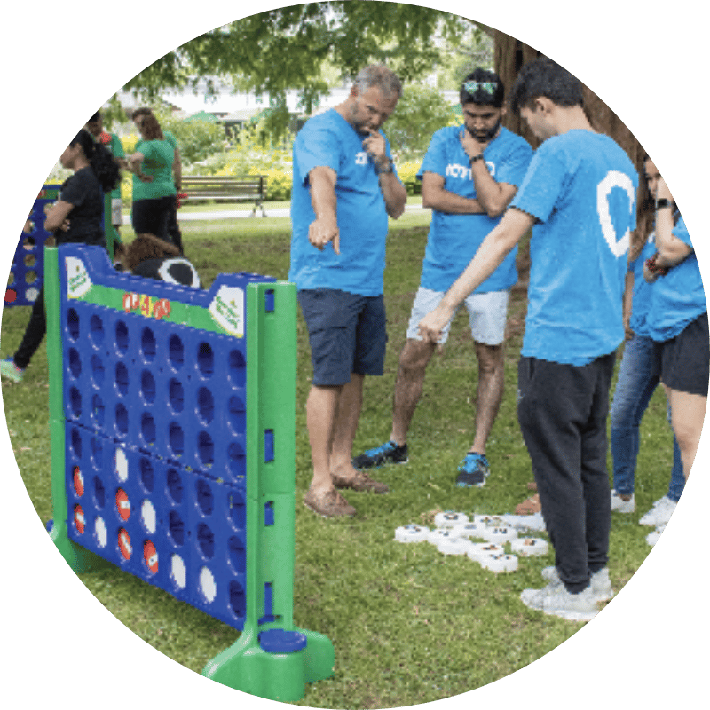 Team in light blue JAM shirts playing giant Connect Four during a JAM in-person event: Field Day