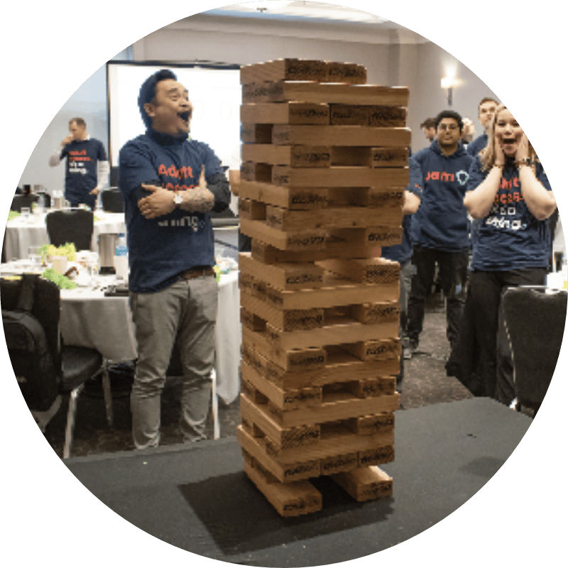 Laughing while playing Giant Jenga during a JAM in-person event: Office Olympics. 