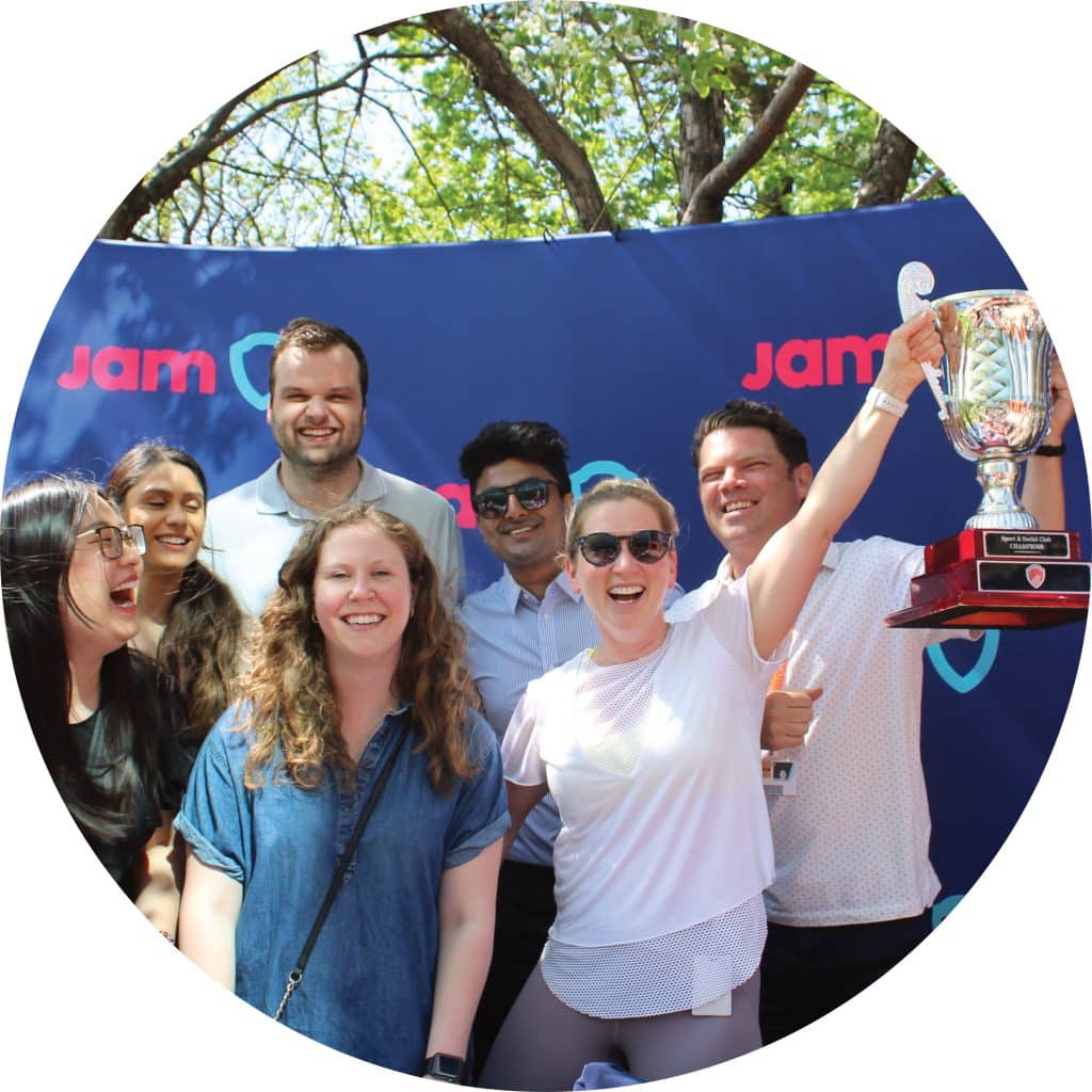Play at work delivers positive experiences, shared laughter and meaningful connections. Group of colleagues posing and smiling for the picture at their JAM team-building event. They are hoisting a trophy in celebration. 