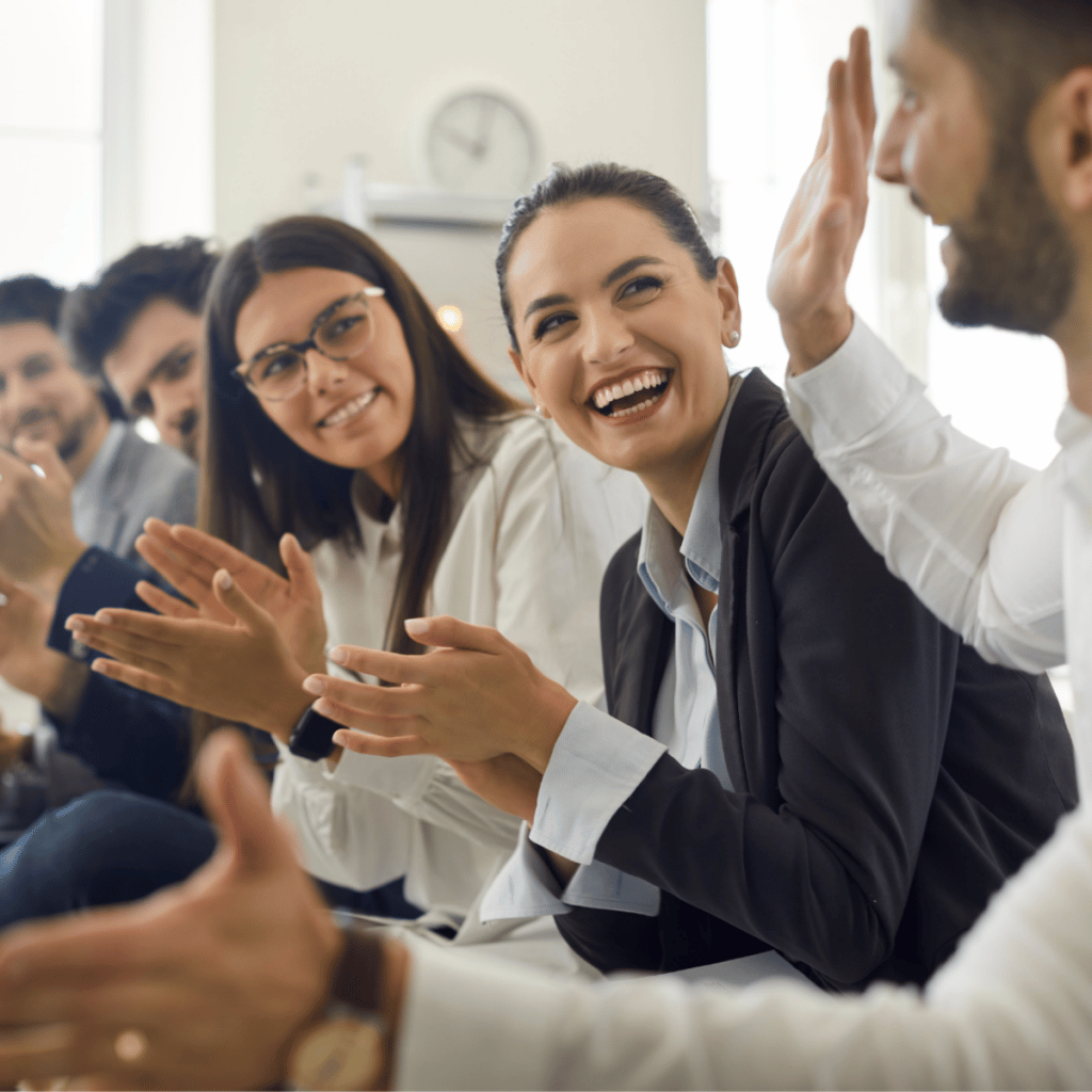 Improved retention, engagement and productivity is why play at work can benefit your organization.  A team of coworkers clap, laugh and solicit high fives. 
